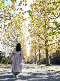 Rear view of woman standing by trees