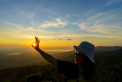 Ok sign silhouette on beautiful sunset above the mountain in the form of woman okay shaped hand 