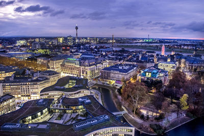 High angle view of illuminated buildings by river against sky