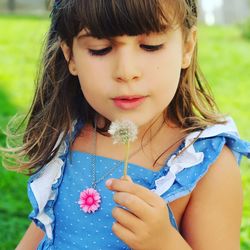 Close-up of girl holding flower standing outdoors