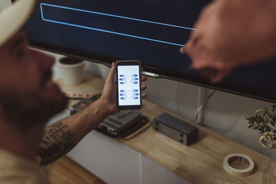 Male maintenance engineer showing app on smart phone to customer at home