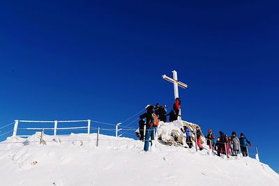 People on snow covered land against clear blue sky