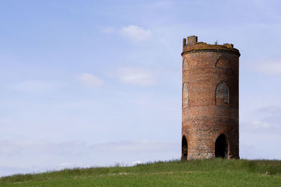 Old ruin on grassy field against sky