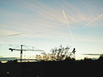 Low angle view of cranes at sunset