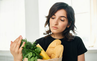 Portrait of young woman holding food at home