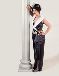 Portrait of beautiful woman wearing dress while standing by architectural column against white background