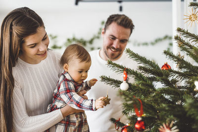 Happy family playing with christmas tree
