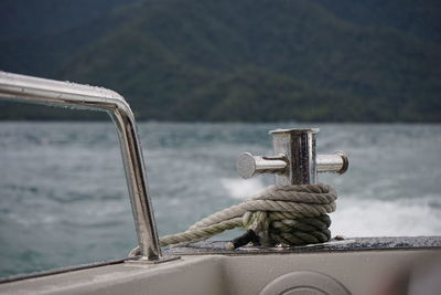 Close-up of rope tied on railing against sea