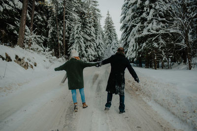 Rear view of friends walking on snow covered trees