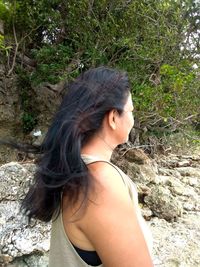 Young woman standing by tree in forest