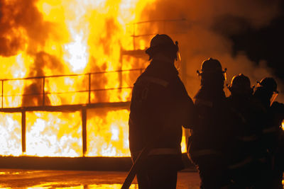 Silhouette firefighters standing against sky