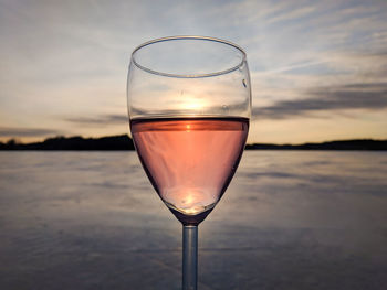 Close-up of beer in glass against sky during sunset