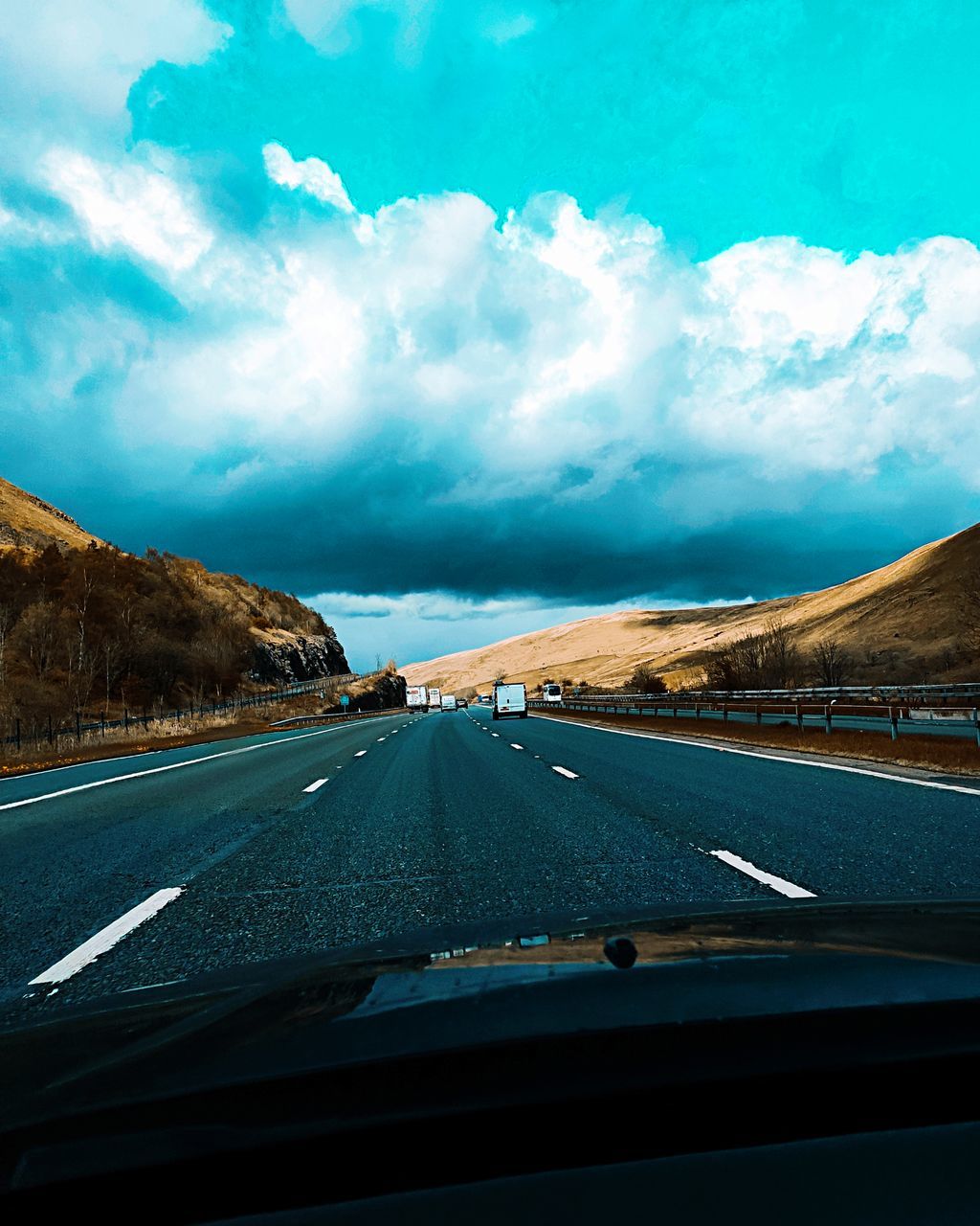 ROAD SEEN FROM CAR WINDSHIELD AGAINST SKY