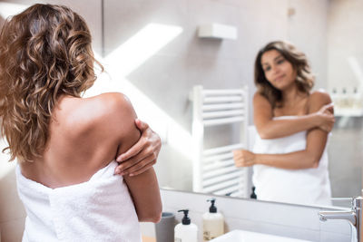 Rear view of women standing in bathroom