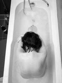 Rear view of naked woman sitting in bathtub