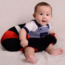 Portrait of cute baby boy sitting on bed at home