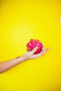 Close-up of hand holding ice cream over yellow background