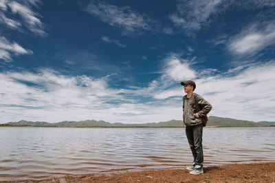 Full length of man standing on lakeshore against sky