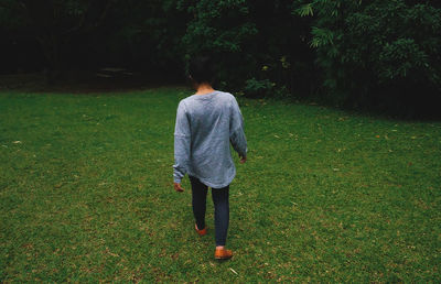 Rear view of woman walking on grass