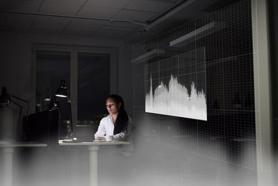 Female finance specialist working in office at night