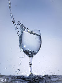 Close-up of water splashing on glass against white background