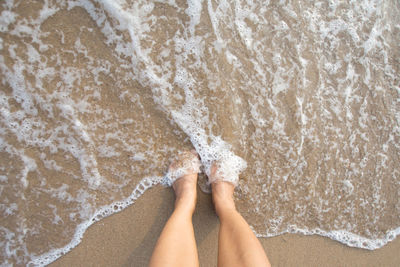 Low section of woman standing on beach