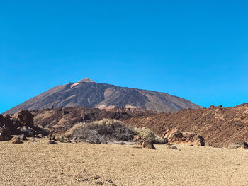 Scenic view of arid landscape against clear blue sky