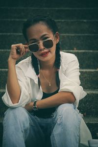 Portrait of young woman sitting against wall