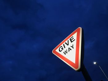 Low angle view of road sign against blue sky