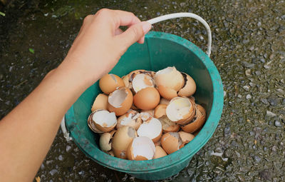 High angle view of hand holding eggs in bowl