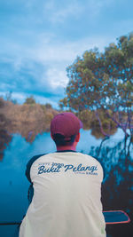 Rear view of man standing by tree against sky