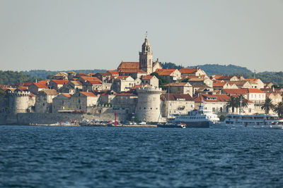 View of townscape by sea against clear sky
