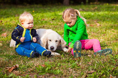 Kids sitting with dog on grass