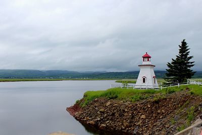 Lighthouse by sea against sky