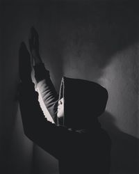 Side view of person sitting against wall