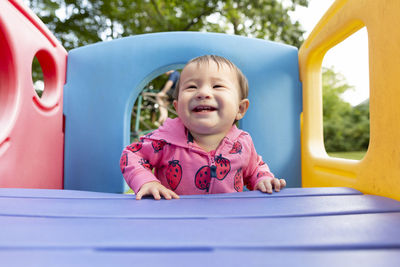 Joyful smiling toddler girl standing in colorful backyard playset