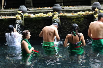 Rear view of shirtless men in water