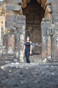 Full length of woman standing against wall