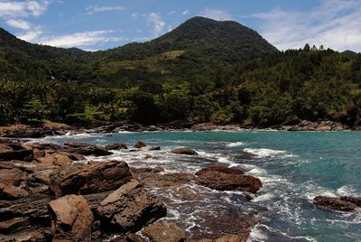 Scenic view of rocks by sea against sky