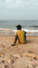 Rear view of man sitting on beach