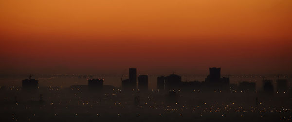 Silhouette buildings against sky during sunset