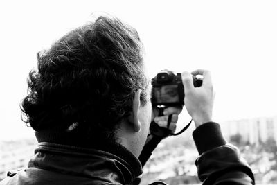 Rear view of man photographing against sky