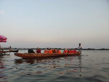 People on boat in sea against sky