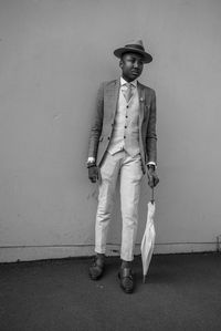 Portrait of man wearing hat standing against wall