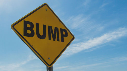 Low angle view of road sign against blue sky