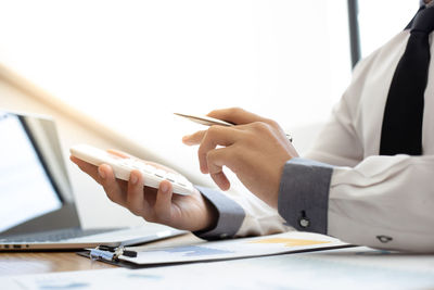 Midsection of man using mobile phone on table