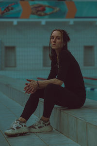 Full length of young woman sitting outdoors