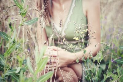 Midsection of woman with flowers on field