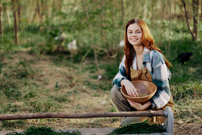 Portrait of smiling woman with food in basket at farm