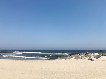 Scenic view of beach against clear blue sky